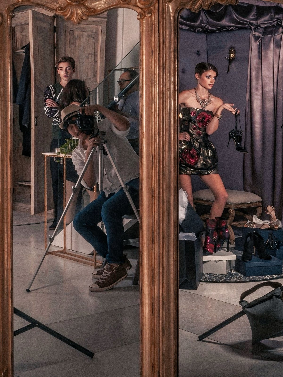 Eric Lee photographing a fitting-room editorial, seen in a gilt mirror