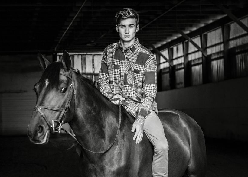 Black and white portrait of a model on horseback in a covered riding arena