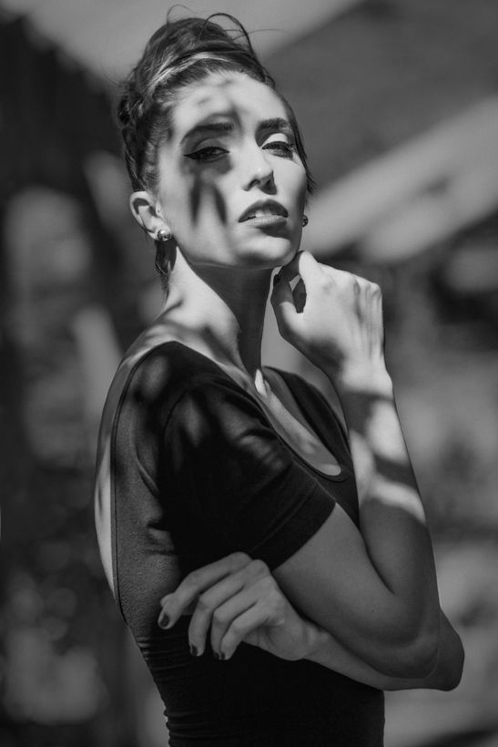 Black and white fashion portrait, dappled light falling across the model's face