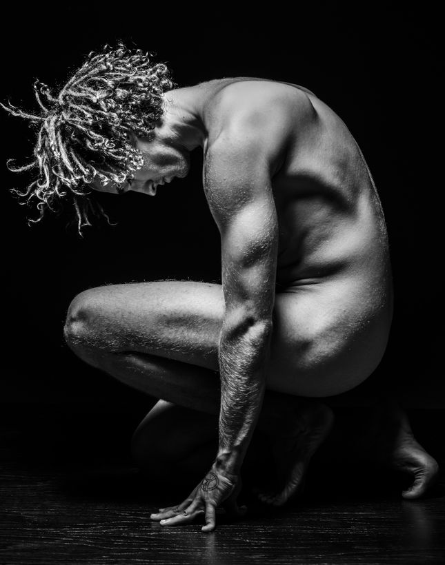 Black and white fine art figure study, crouched form lit against a dark ground