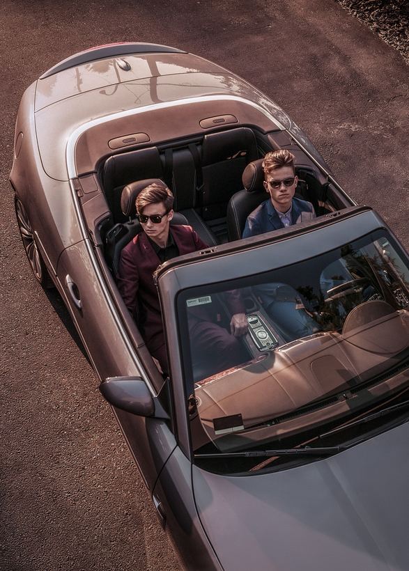 Overhead menswear image, two models in tailoring seated in an open-top car